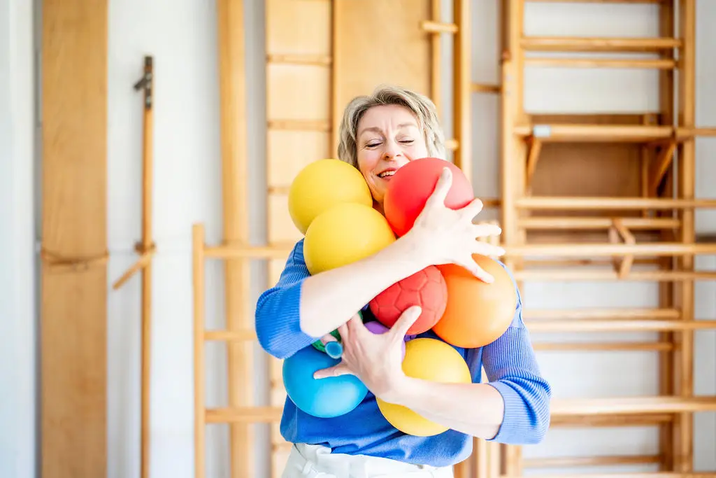 Josanne de Graaf draagt een armvol gekleurde ballen door de gymzaal