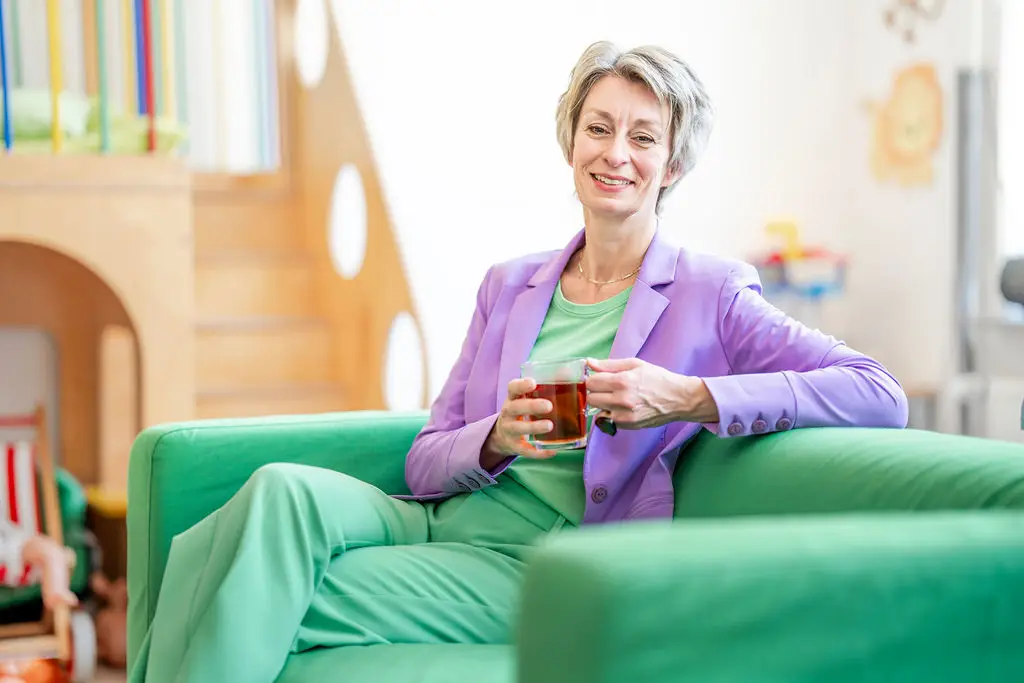 Josanne de Graaf zit met een kop thee op een groene bank